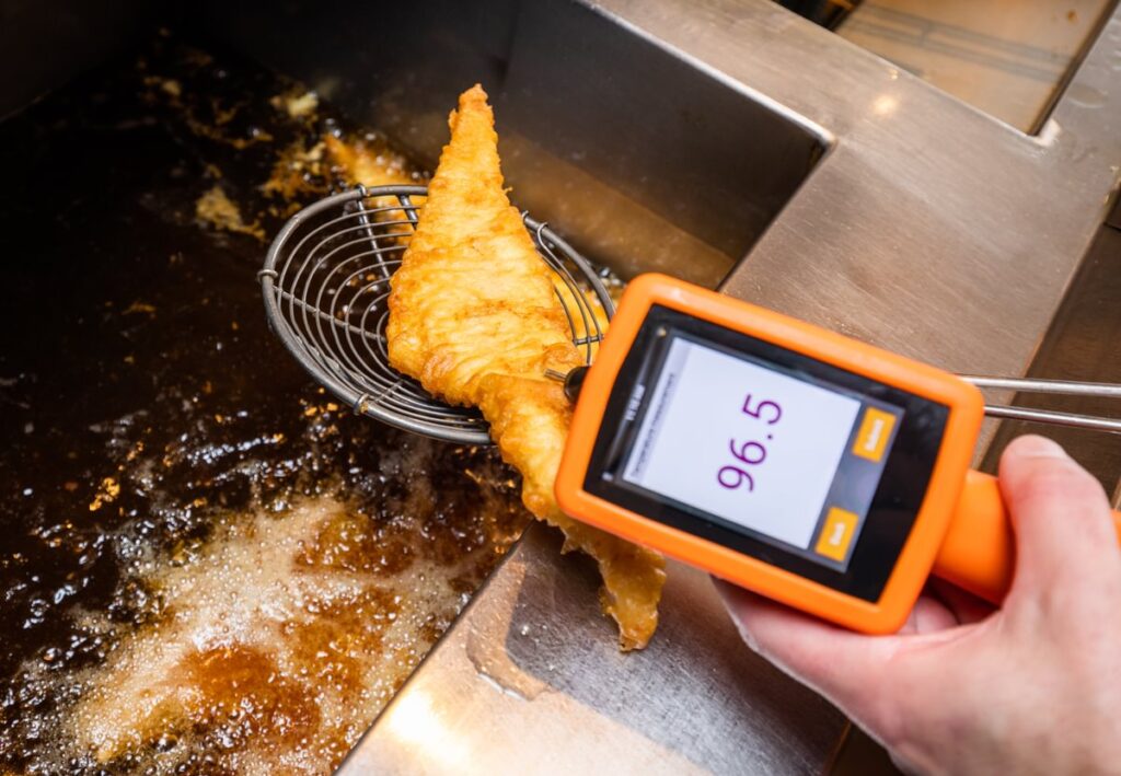 A piece of fried fish being temperature checked using a temperature probe