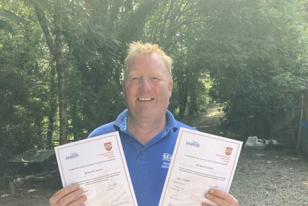 A person stood up holding two certificates