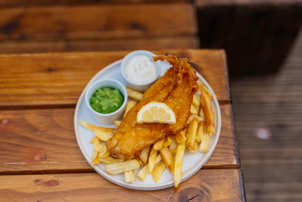 A plate of fish, chips, peas and tartare sauce