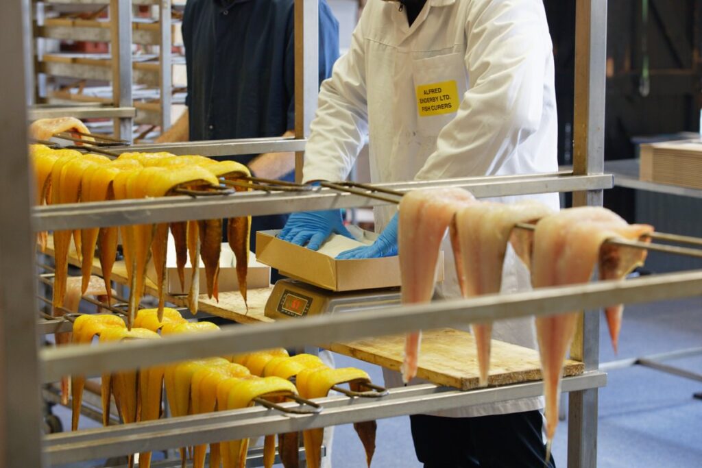 Smoked Haddock fillets being packed into a cardboard box by a seafood worker