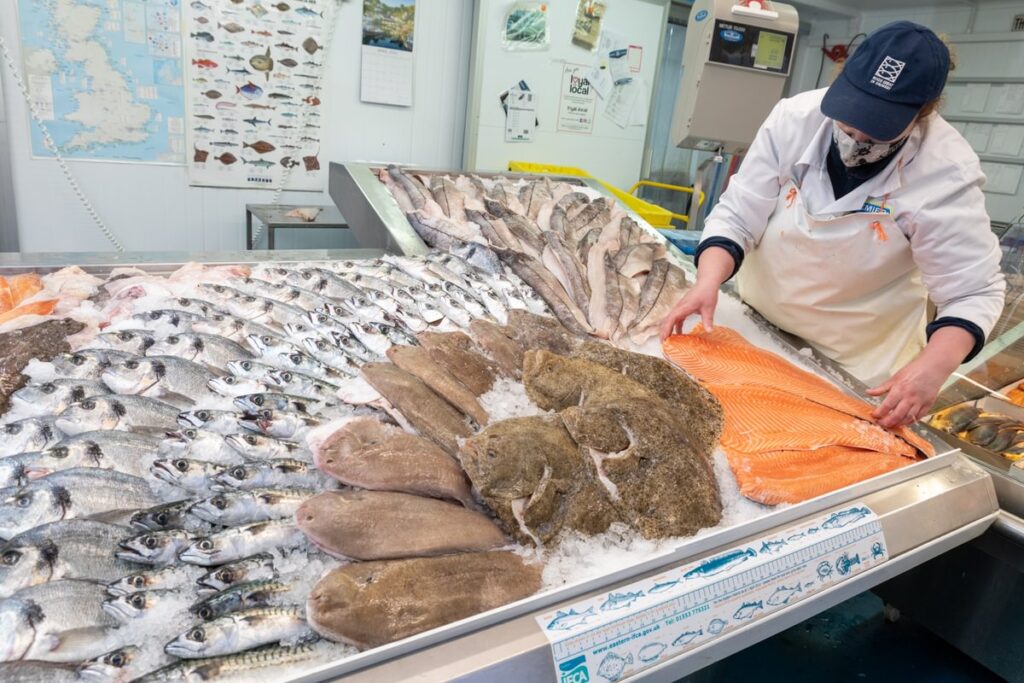 A display of fish with a fishmonger stood to the right of the display