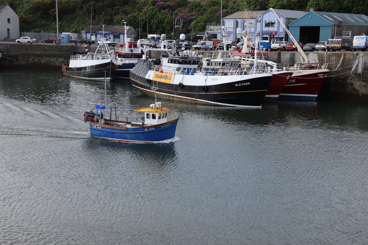 Aerial view of small fishing vessel underway with a harbour