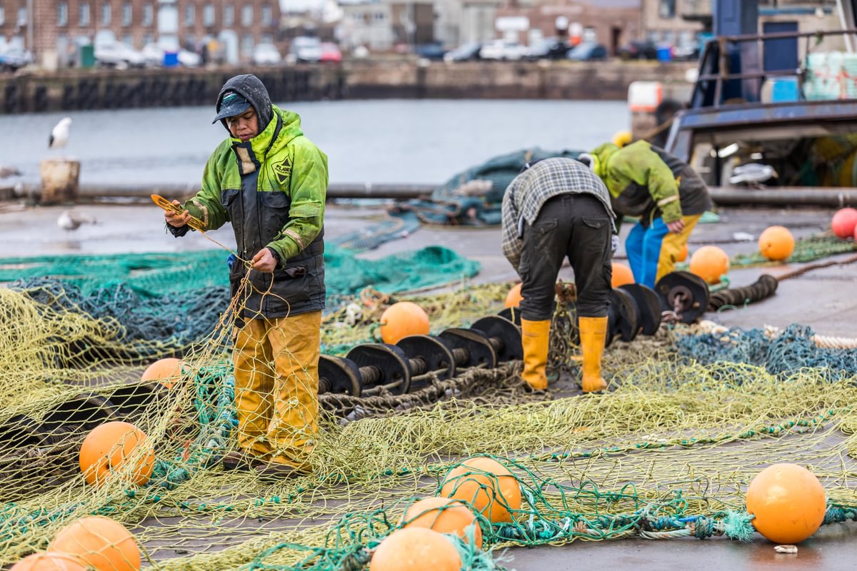 Men mending a fishing net on the quay side